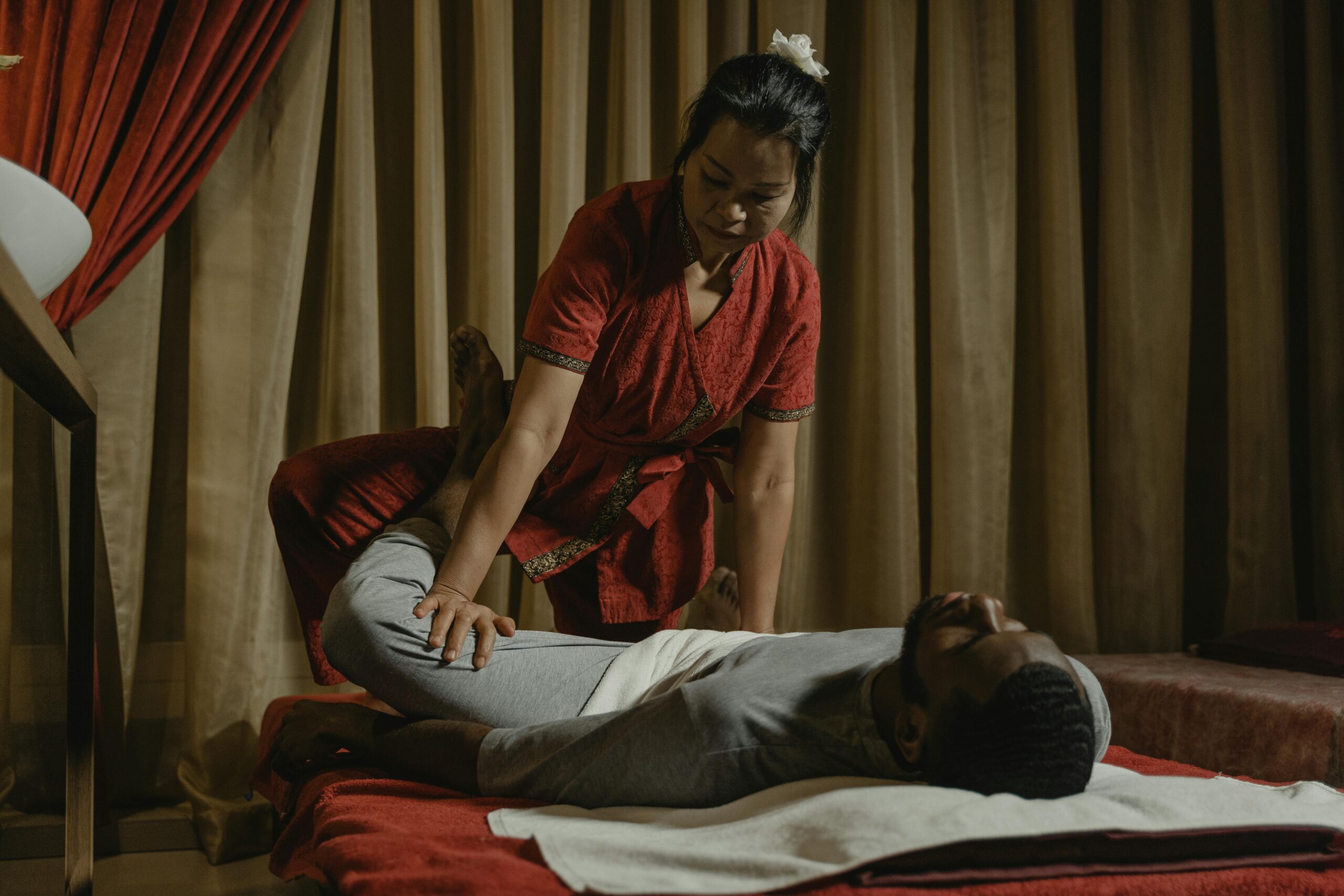 Services Professional therapist performing leg stretch on client in a serene massage room setting.